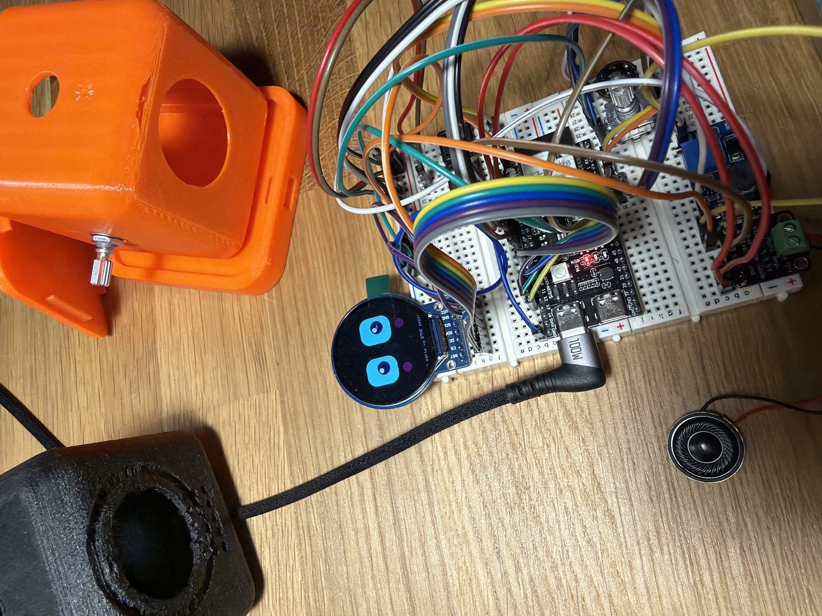 Foto del prototipo reale di FARO: display tondo con una faccina, breadboard con la scheda ESP32, manopola, altoparlante e scocche stampate in 3D